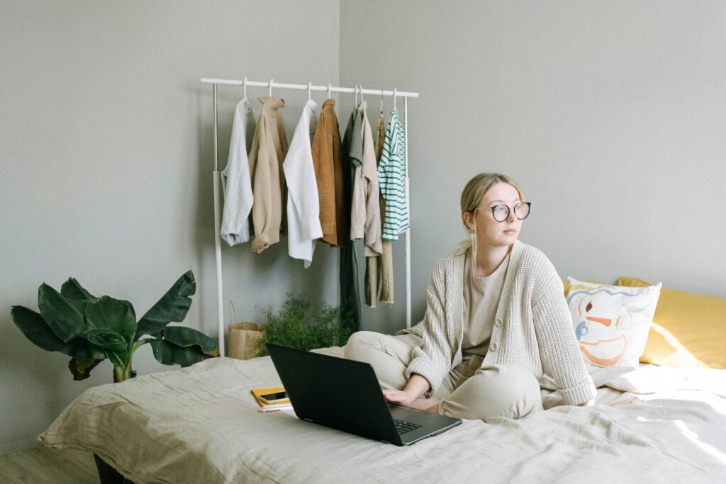 Einsamkait im Homeoffice, eine Frau sitzt mit Laptop auf dem Bett